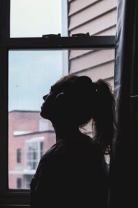 Silhouette of sad woman looking out window