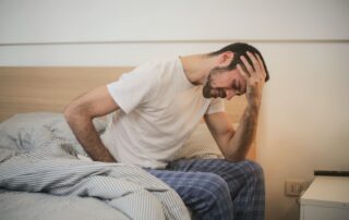 Man who cannot sleep sitting on side of bed with head in hand