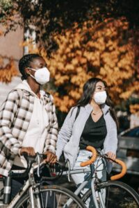 Two women wearing masks with bicycles