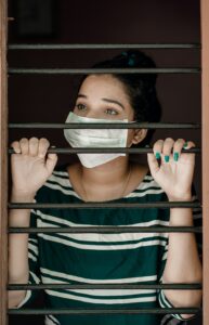 Woman looking outside between window bars