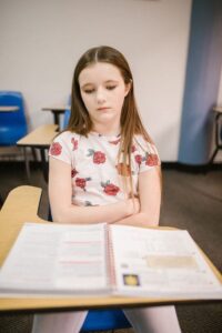Girl sitting in desk arms folded looking down