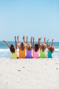 Group of women on beach with arms raised
