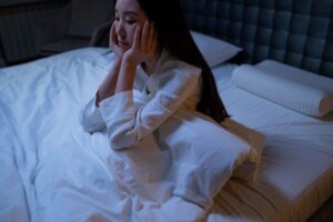 woman sitting up in bed with head in hands