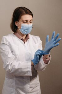 Woman in lab coat, gloves and mask