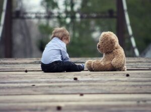 Child with head down and teddy bear