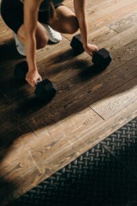 Person holding weights on wood floor