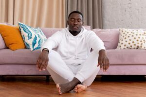 Tranquil man sitting with closed eyes and crossed legs on floor