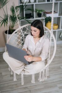 Woman sitting in hanging chair with laptop