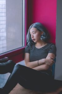 Woman with sad expression sitting in corner looking out window