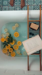 Filled bathtub with citrus slices and book