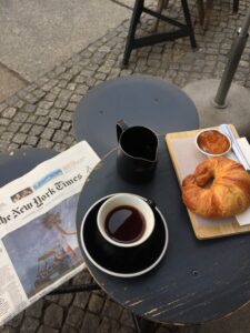 Newspaper with coffee and croissant on table