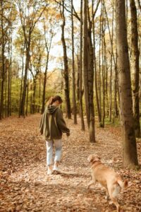 Woman with dog walking through leaves