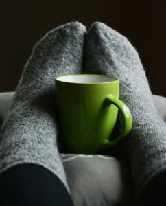 Feet in gray socks with green mug between them