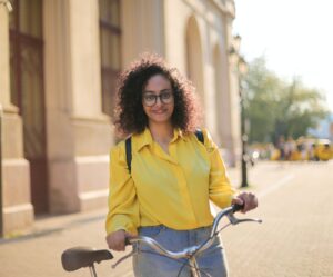 Woman with bicycle in yellow shirt and jeans