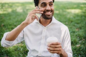 man holding coffee cup and talking on cell phone