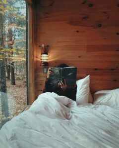 Person sitting up in bed reading a book