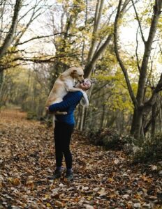 Woman on fall trail with dog in arms