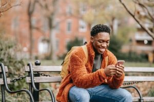 Man on park bench smiling looking at cell phone
