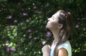 Woman next to large tree taking a deep breath