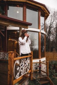 Woman standing outside on deck with warm drink in hand