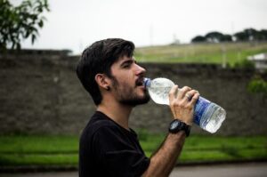 Man outside drinking from a bottle of water