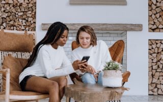 Two women sitting in chairs looking at phone