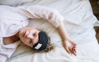 Woman lying in bed with eyes open wearing eye mask