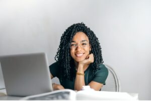 Woman sitting in front of laptop smiling with chin on hand