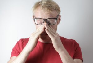 Man holding his glasses up on his nose with eyes closed