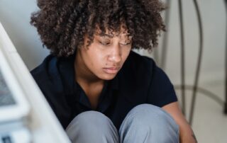 Woman sitting in corner of desk on floor