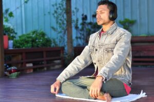 Man wearing headset and sitting on towel meditating