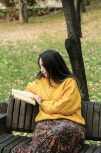 A woman sitting on park bench reading
