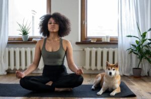 Woman sitting on yoga mat in meditation with dog