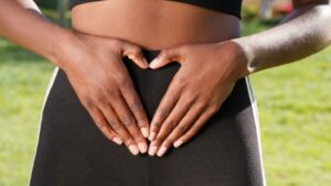 Person holding hands in heart shape over belly