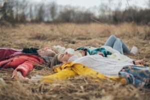 3 people laying in a circle in a field holding hands and smiling