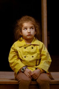 Child in yellow jacket with frown