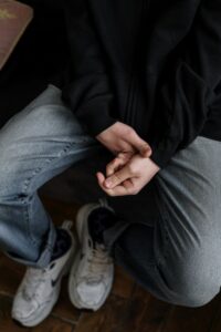 Shoulders down view of person in jeans and black sweatshirt holding hands