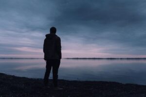 Person in silhouette standing and looking over a large lake