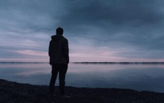 Person in silhouette standing and looking over a large lake
