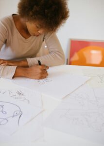 Woman looking down at paper on table and drawing