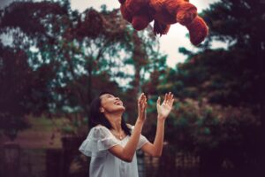 Smiling woman with teddy bear thrown in air